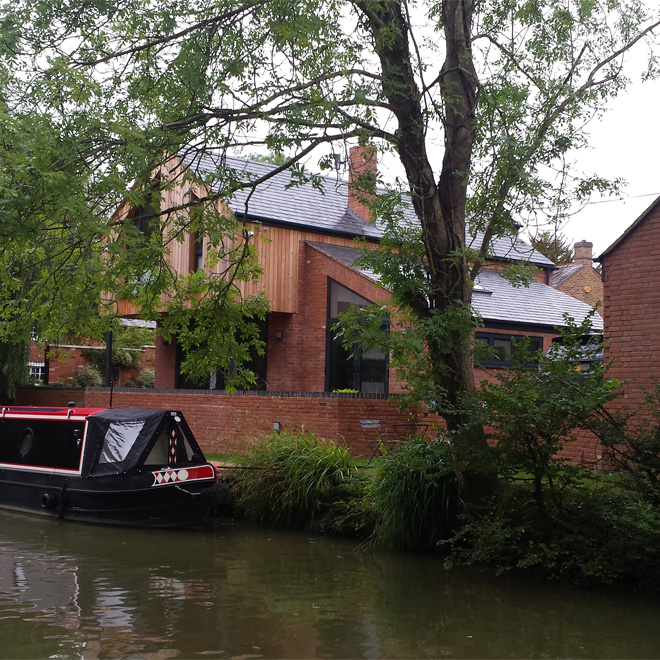 A canalside house, with a canal boat moored next to it.